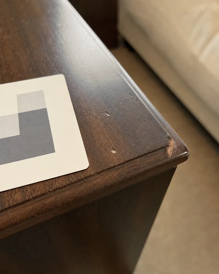 A small chip on a bedside table, a scale card set beside it